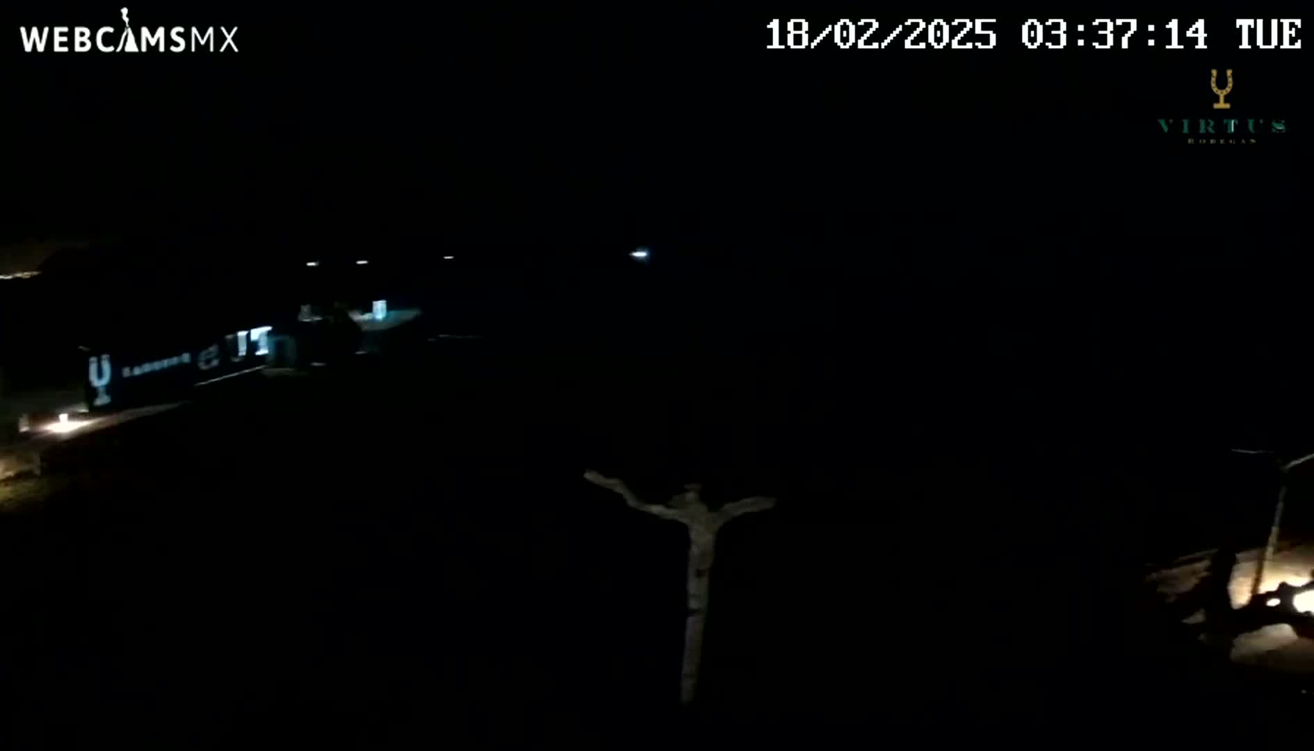 A dark, nighttime scene shows a dimly lit building and a crucifix-shaped object, under a clear sky.