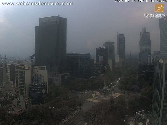 A hazy, high-angle view of a city skyline with several skyscrapers and a large monument in a plaza.