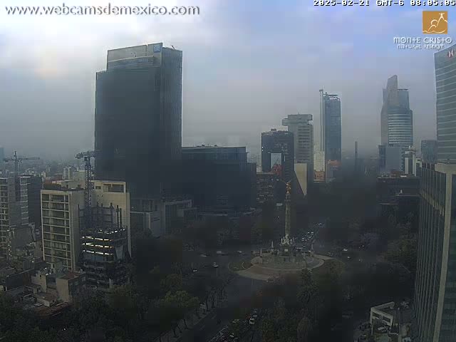 A hazy, overcast view of a city featuring numerous tall buildings and a large monument in a central plaza.