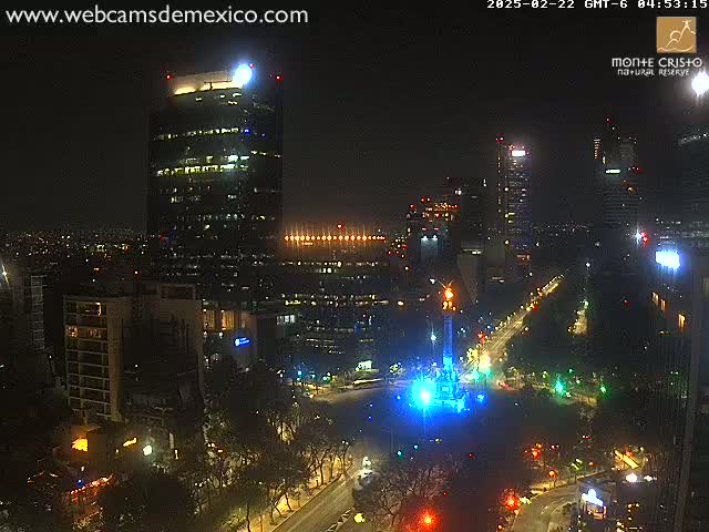 A nighttime cityscape with illuminated buildings and streets, featuring a monument bathed in blue light.
