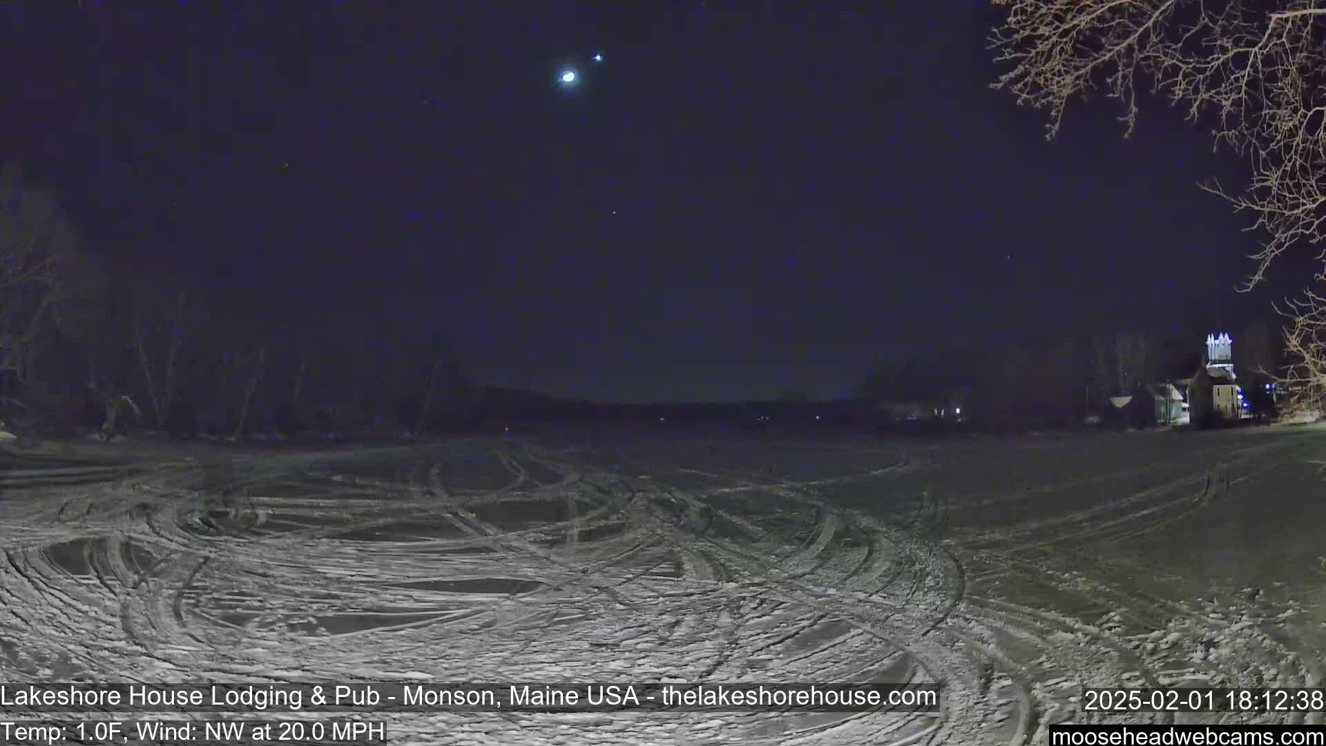 A snow-covered field with tire tracks under a dark, clear night sky showing some stars and a bright planet, with a light wind blowing from the northwest at 20 mph and a temperature of 1 degree Fahrenheit.