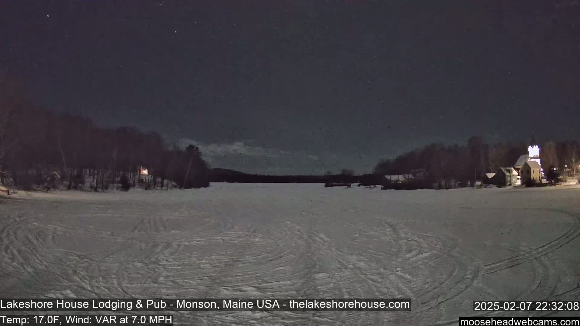 A snow-covered expanse stretches across a frozen lake under a dark, starry night.
