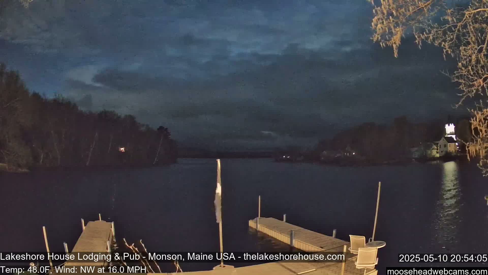 A dark, nighttime view of a calm lake with a dock in the foreground, under a mostly cloudy sky with a northwest wind at 16 mph and a temperature of 48°F.