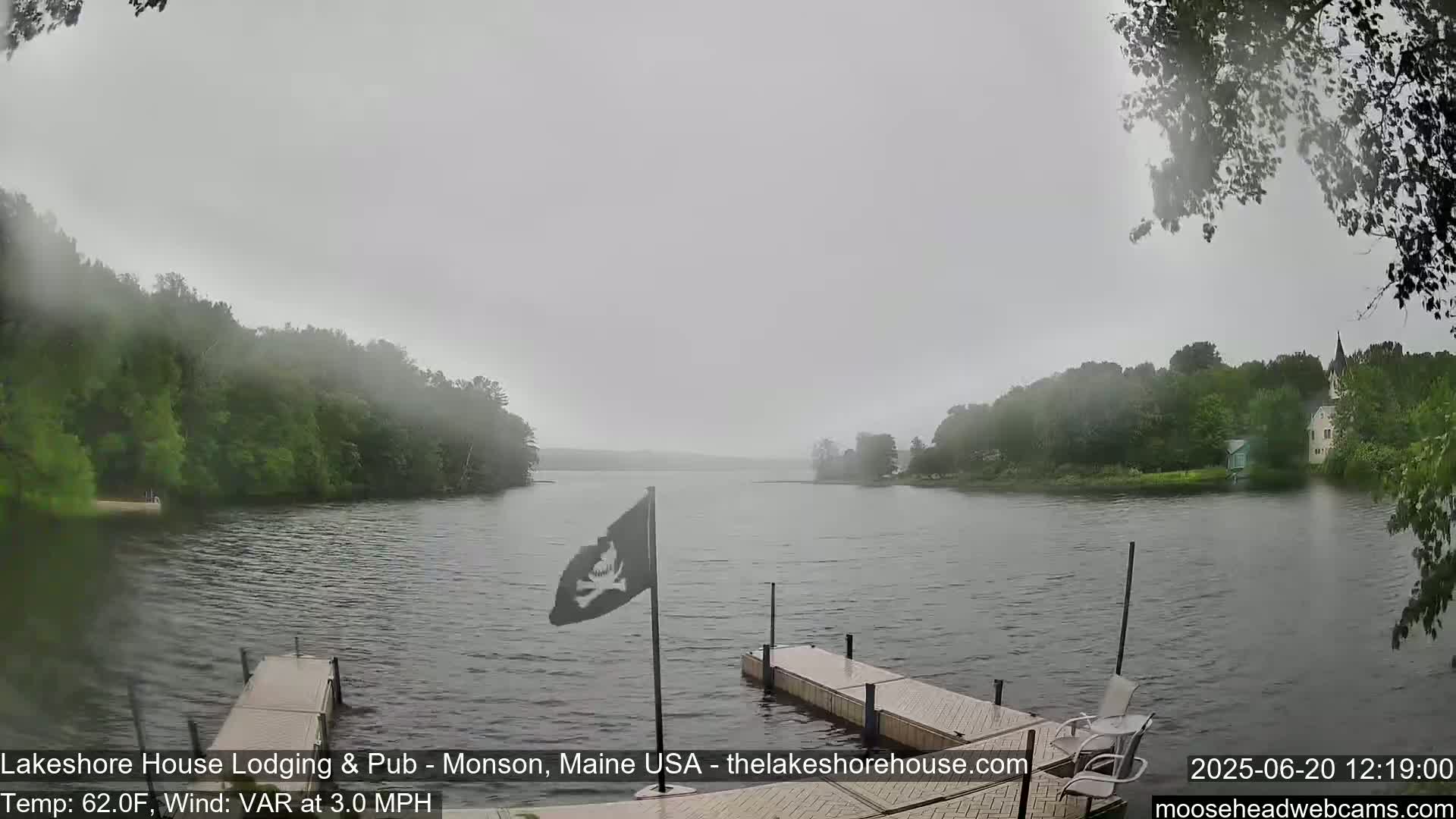 A calm lake is shrouded in fog, with two docks and a pirate flag visible in the foreground.