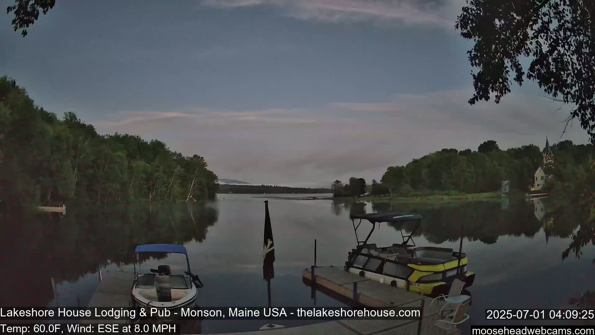 Two boats are moored at a dock on a calm lake under a twilight sky with a gentle ESE wind.