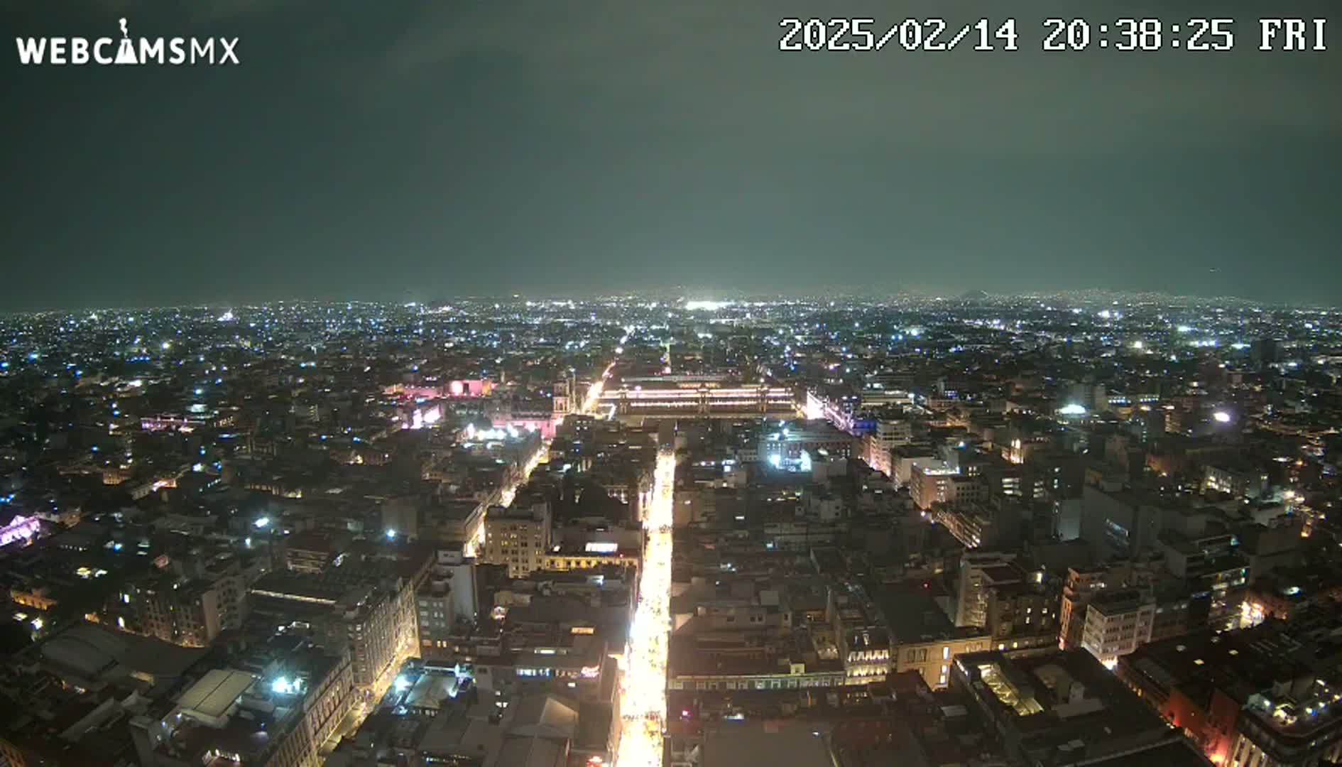 A nighttime aerial view of a brightly lit city under a dark, clear sky.
