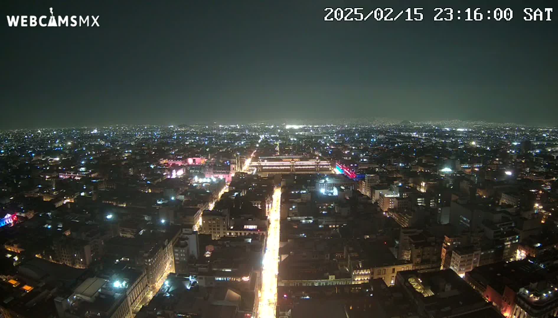 A nighttime aerial view of a sprawling city with brightly lit streets and buildings under a clear sky.