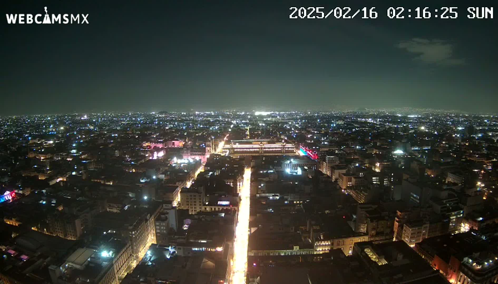 A nighttime aerial view of a sprawling city with brightly lit streets and buildings under a clear sky.