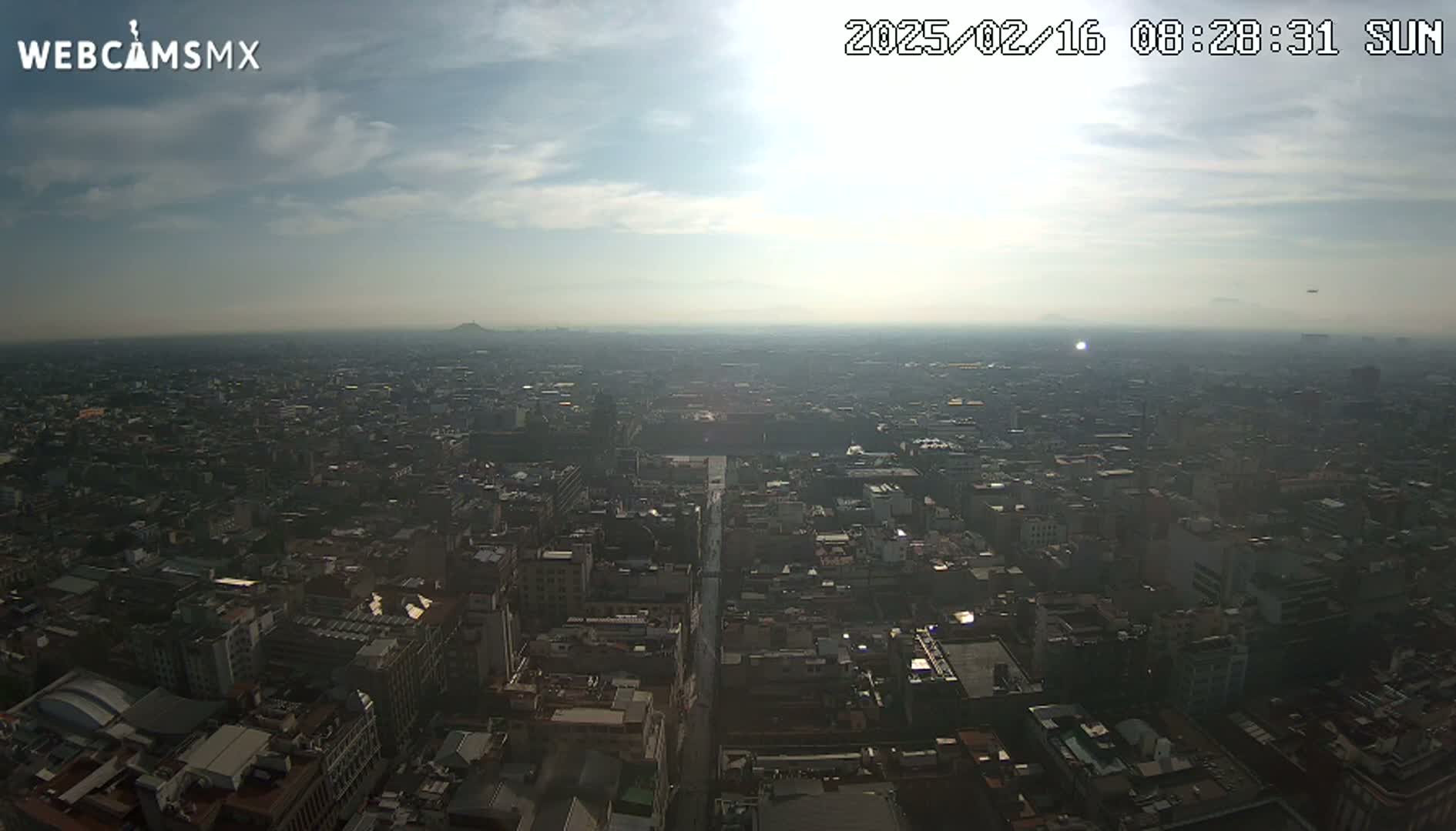 A hazy, sunny day reveals a sprawling cityscape extending to the horizon.