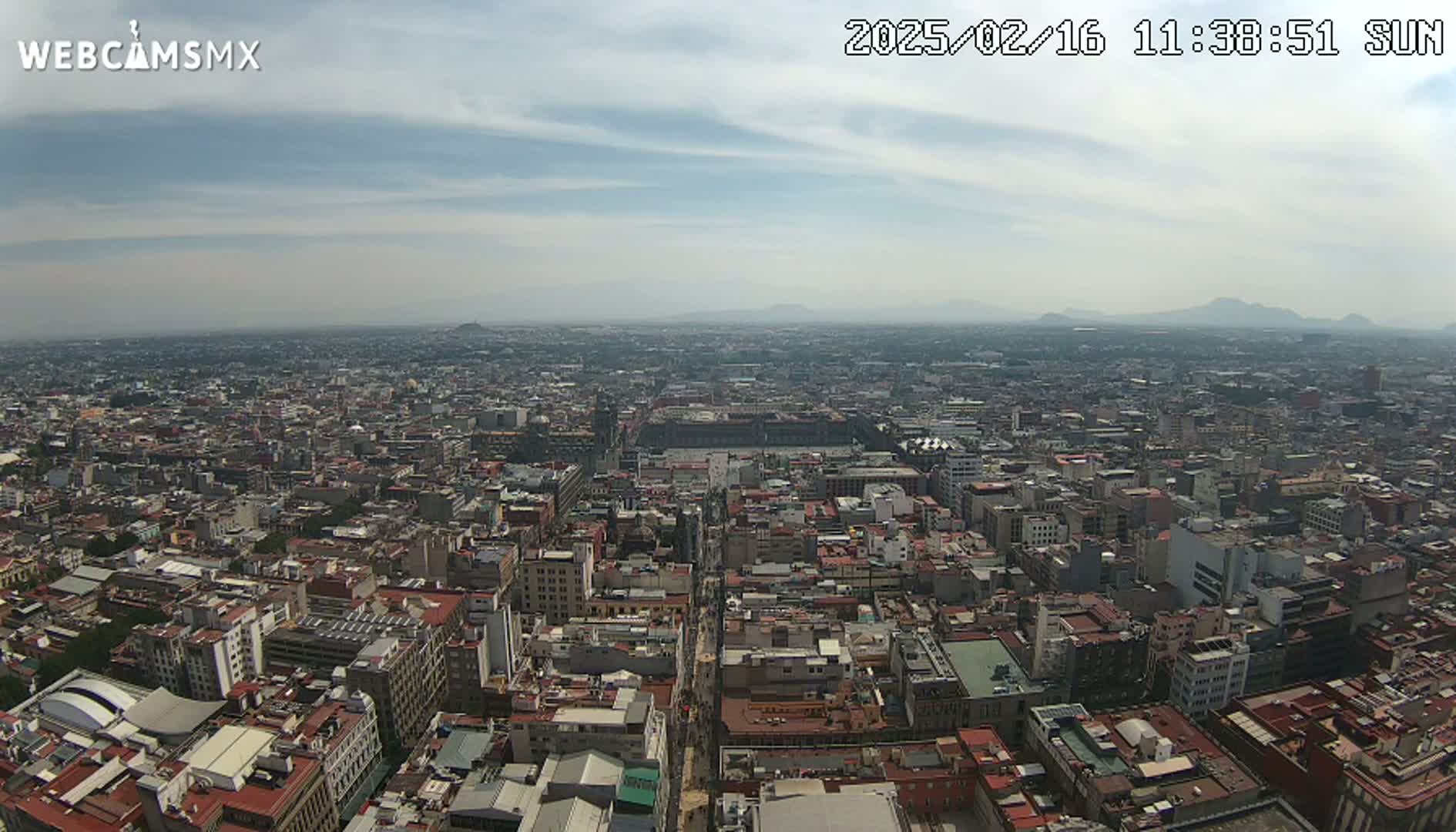 A hazy, sunny day reveals a sprawling cityscape stretching to distant mountains.