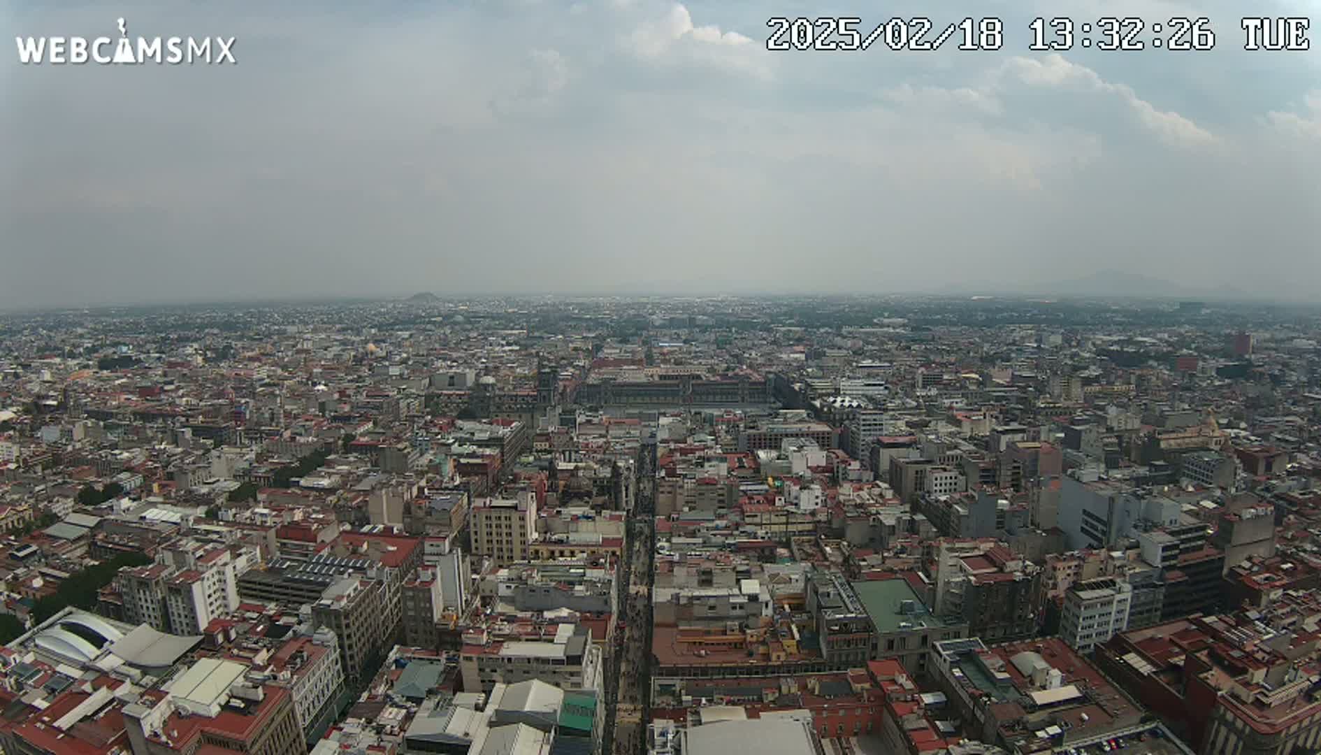 A high-angle, long shot shows a sprawling city under a hazy, overcast sky.