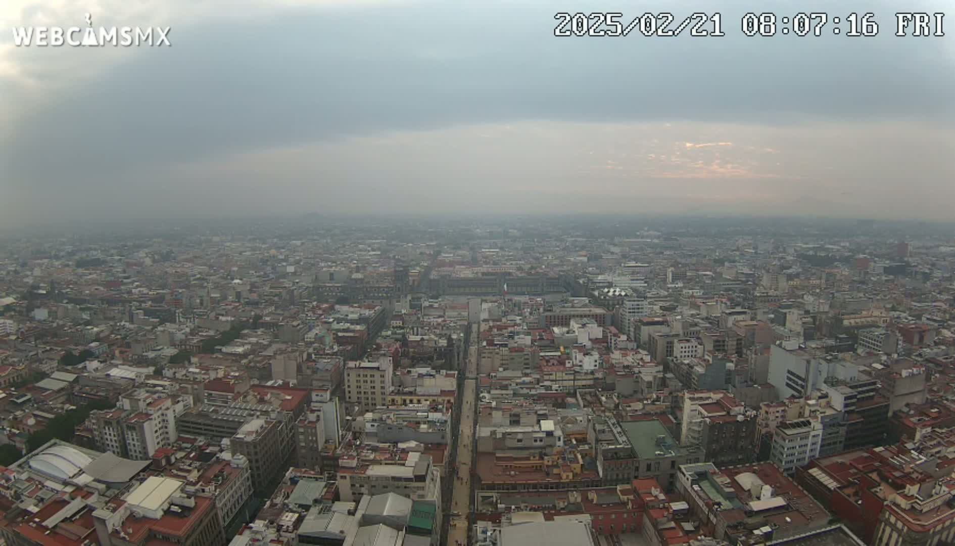 A hazy, overcast day reveals a sprawling cityscape viewed from a high vantage point.