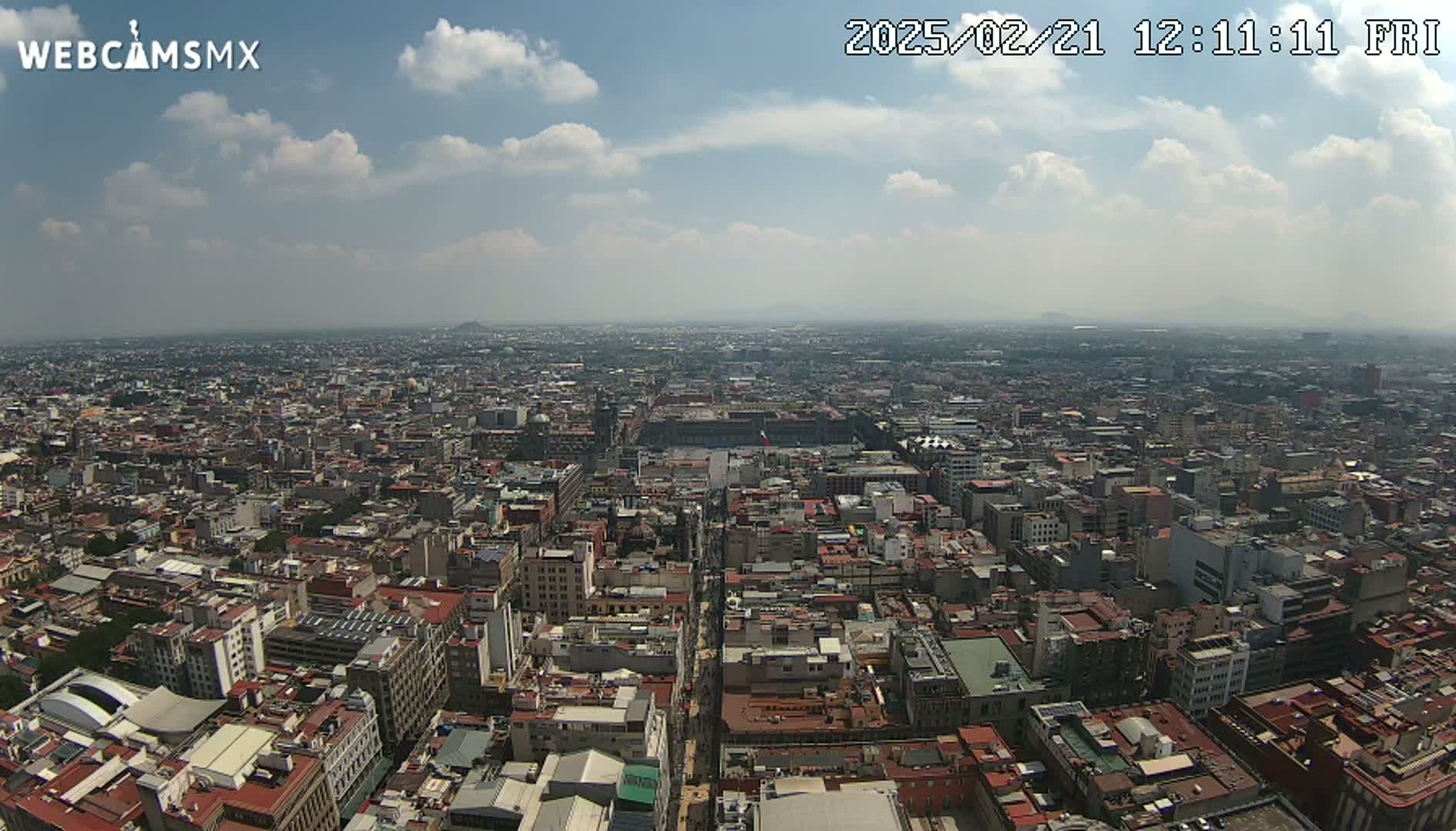 A high-angle, long shot of a sprawling city under a partly cloudy sky.