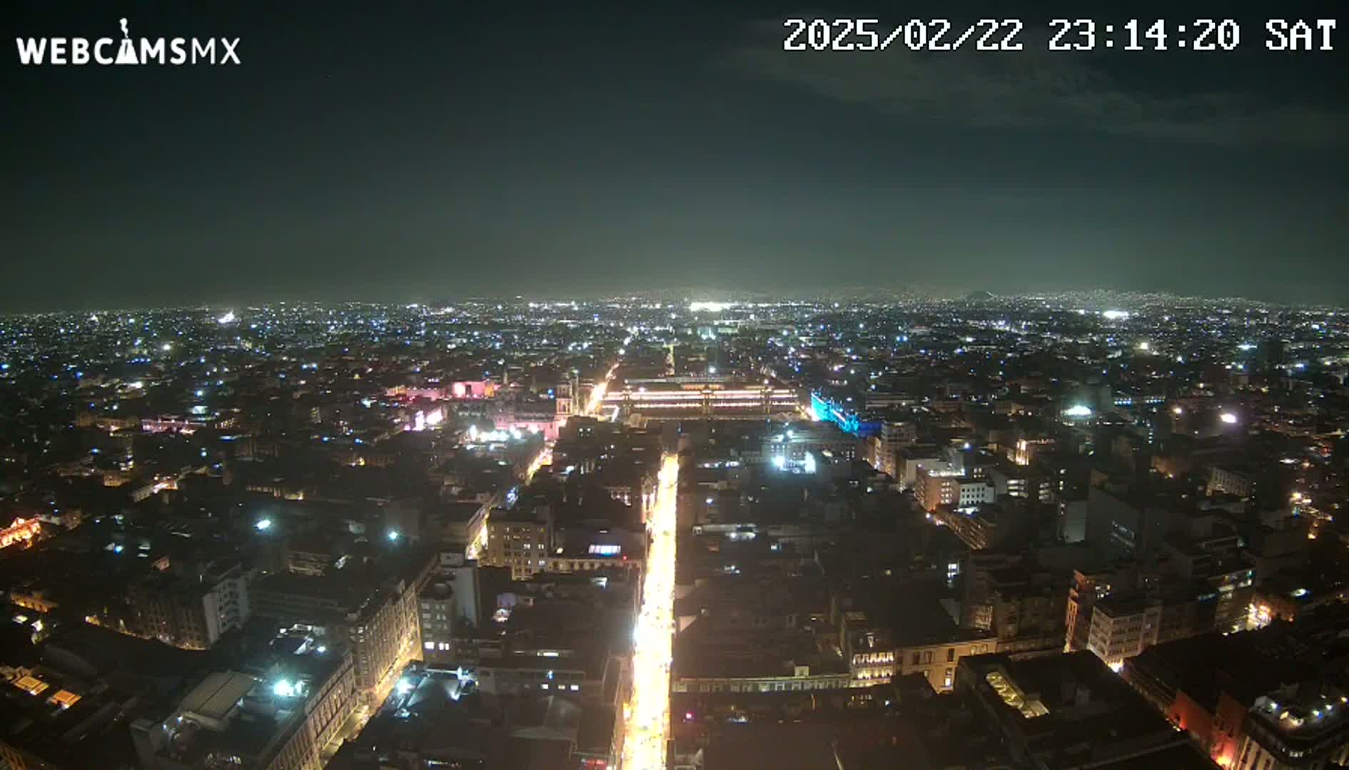 A nighttime aerial view of a sprawling city with brightly lit streets and buildings under a clear, dark sky.