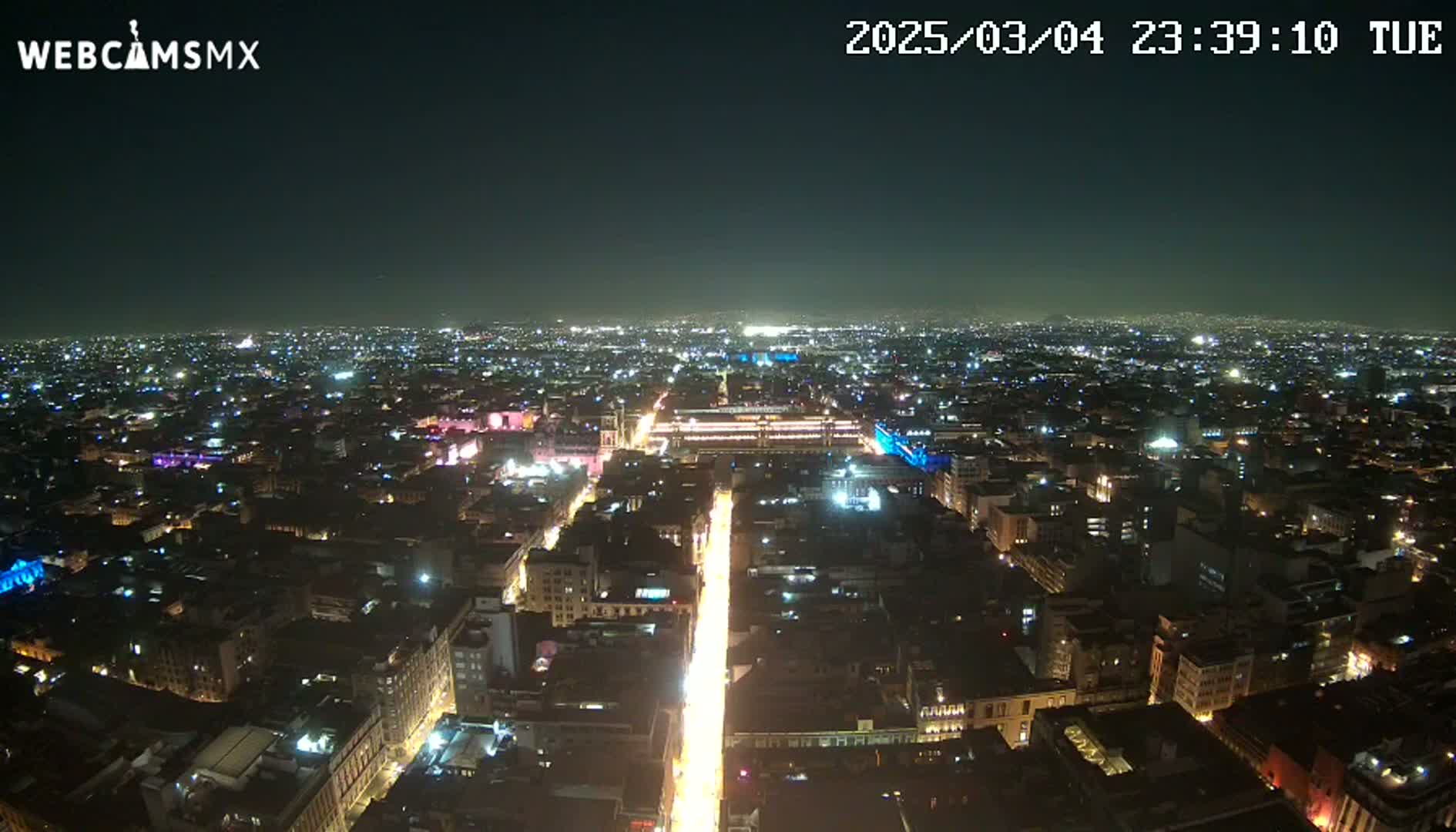 A brightly lit city at night stretches to the horizon under a clear, dark sky.