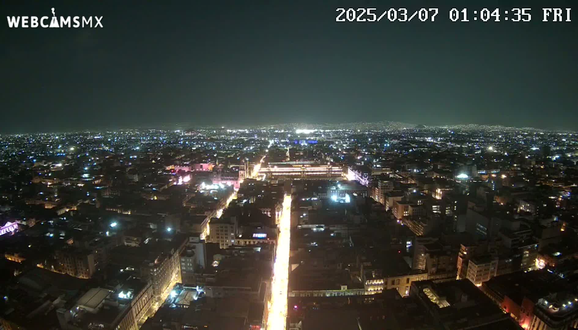 A nighttime, aerial view shows a brightly lit city sprawling across a vast area under a clear, dark sky.