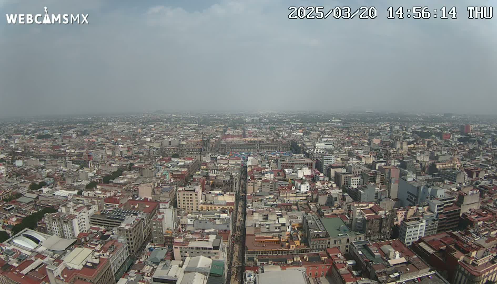 A hazy, high-angle view shows a vast urban expanse of densely packed buildings stretching to the horizon.