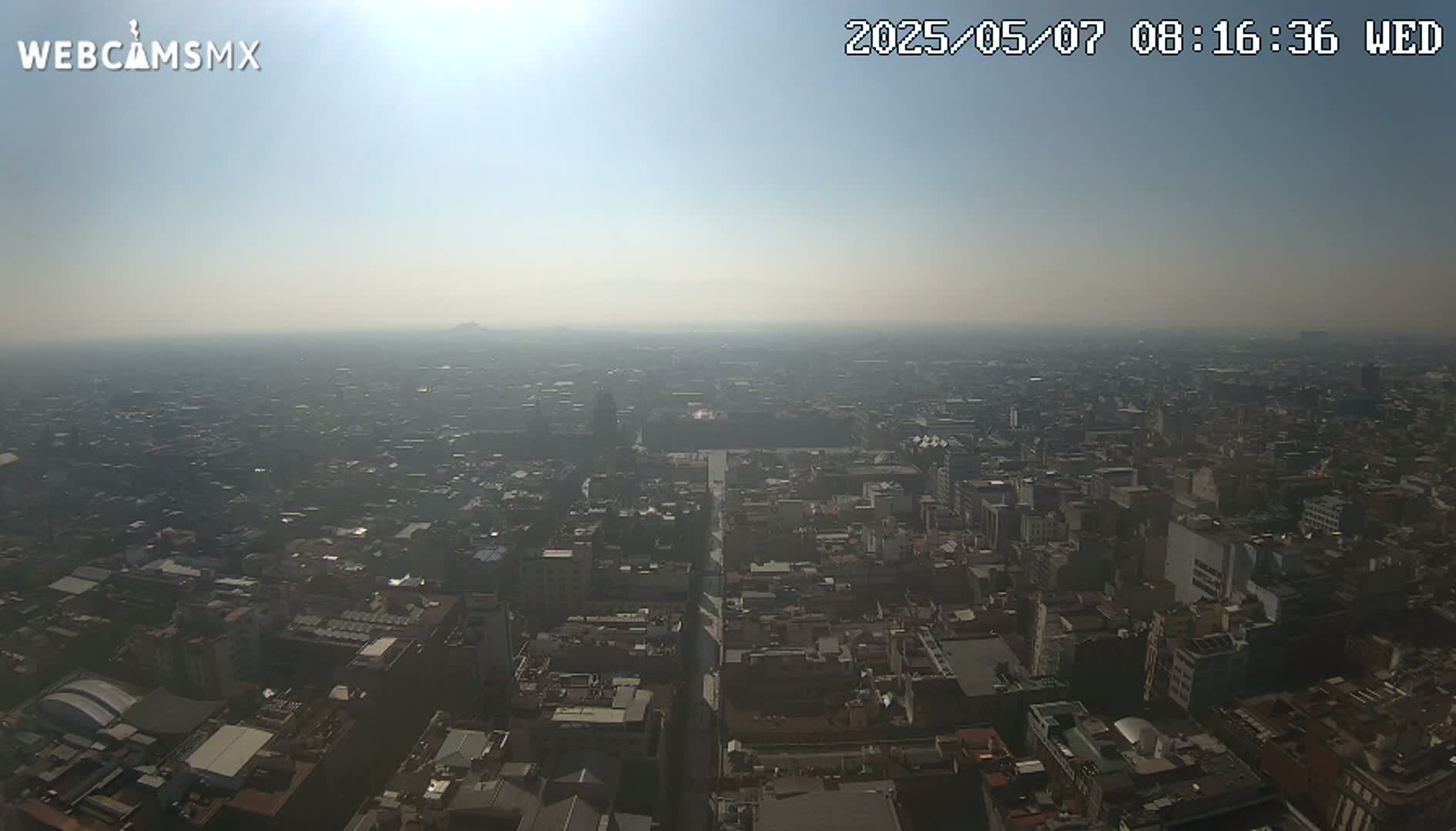 A hazy, sunny day reveals a sprawling cityscape extending to the horizon.