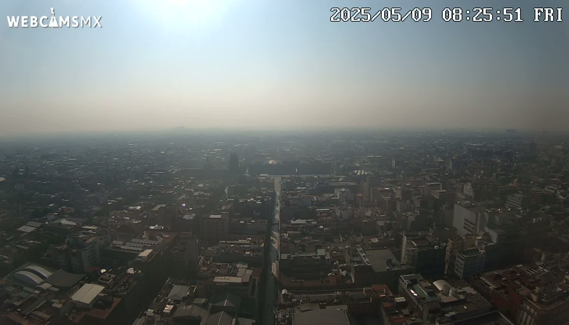 A hazy, sunny, high-angle view of a sprawling city.