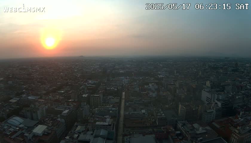 An aerial view of a large city at sunset under hazy conditions.