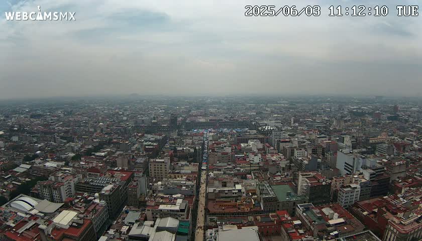 A hazy, overcast day reveals a vast, densely populated cityscape stretching to the horizon.