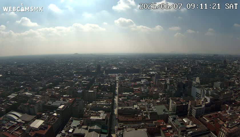 A hazy, sunny day reveals a vast, sprawling city with numerous buildings extending to the horizon.