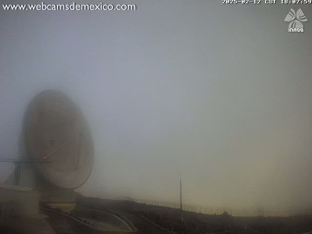 A large parabolic antenna is partially obscured by heavy fog.