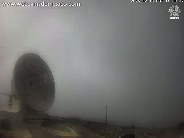 A large satellite dish is visible in a foggy outdoor setting.