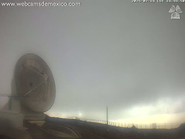A large satellite dish is visible on a foggy, overcast day.