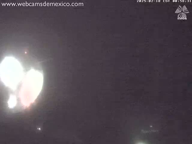 A bright, blurry light source, possibly a firework or flare, illuminates a dark night sky.
