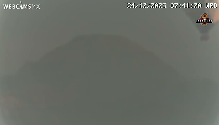 A large, dark silhouette of a pyramid dominates the foreground under a clear night sky, flanked by the scattered lights of a distant city.