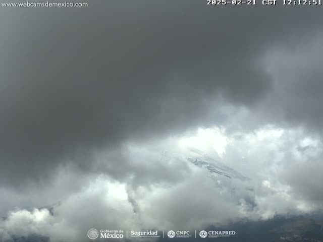 A snow-capped mountain peak is partially obscured by a thick layer of dark, overcast clouds.