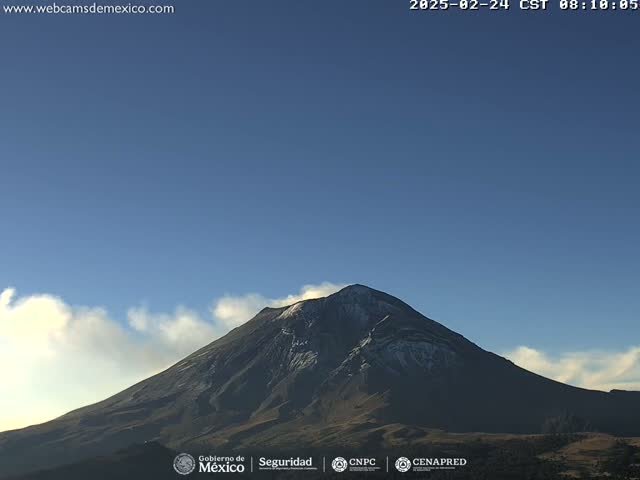 A snow-capped volcano is visible under a clear blue sky with a few wispy clouds.