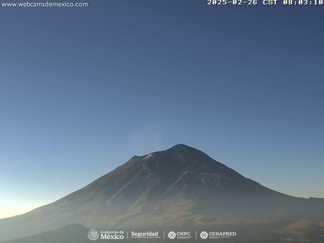 A large, dark mountain with a hint of snow near its peak is visible under a clear, light-blue sky.