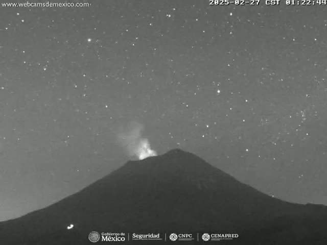 A nighttime, starlit view of a volcano emitting a plume of smoke.