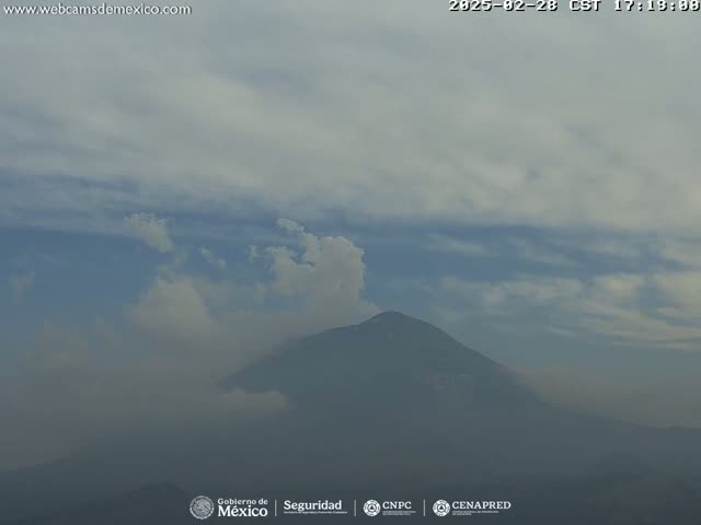 A hazy, partly cloudy sky hangs over a dark, distant mountain.
