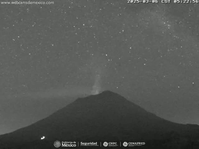 Under a clear, starry night sky, a volcano emits a faint plume of smoke or ash.