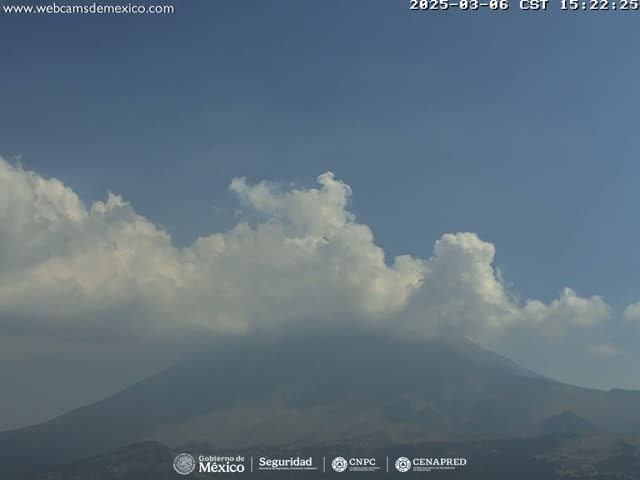 A hazy mountain is visible beneath a partly cloudy sky.