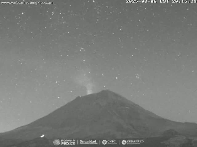 A volcano erupts under a clear, starry night sky.