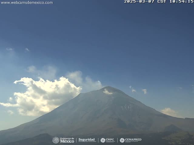 A large volcano is visible under a mostly clear sky with a few scattered clouds.