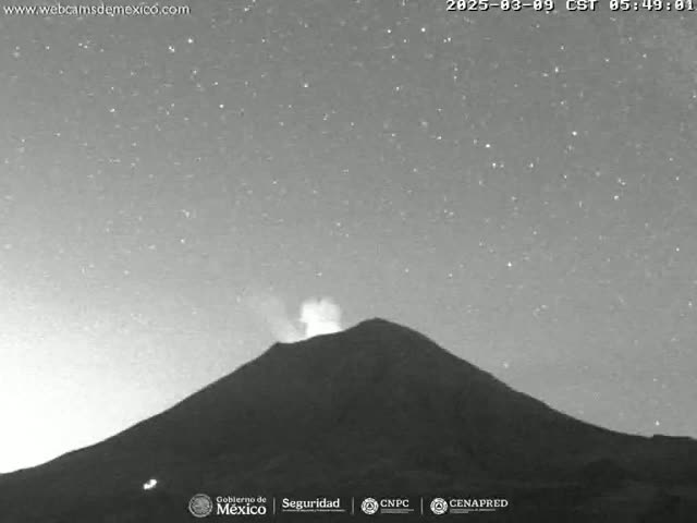 A volcano is erupting under a clear, starry night sky.