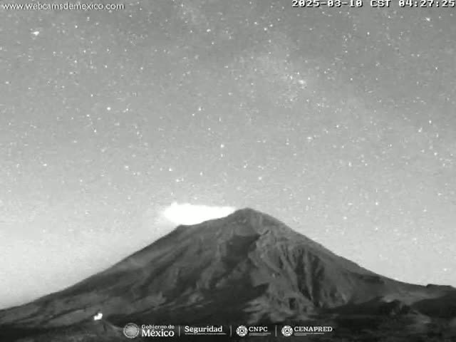 A large, dark mountain is shown under a night sky full of stars, with a faint glow emanating from near its peak.