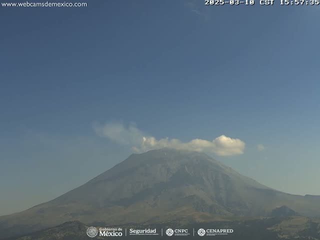 A large, hazy mountain is visible under a clear, mostly blue sky with a few small clouds.