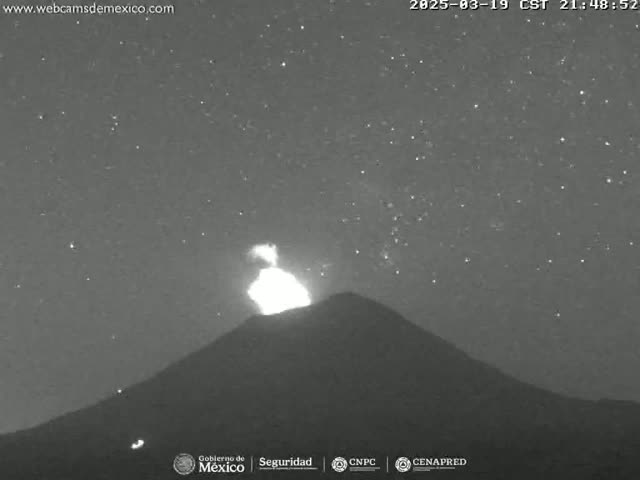 A nighttime, long shot of a volcano erupting under a starry sky.