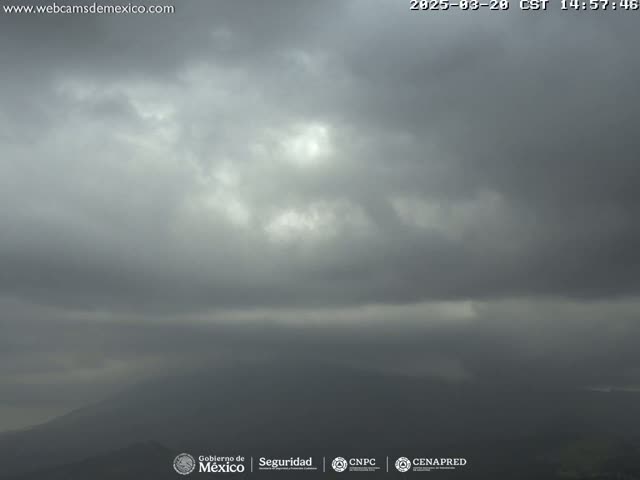 A mostly cloudy, overcast sky hangs over distant, hazy mountains.