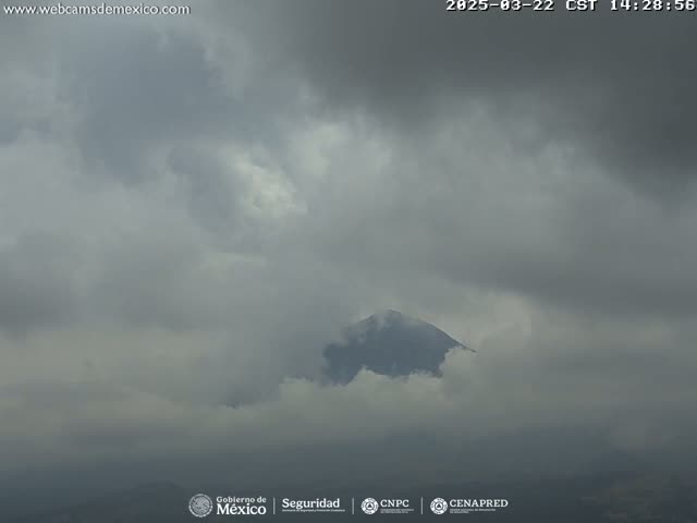 A dark, cloudy sky obscures a mountain peak partially shrouded in low-lying clouds.