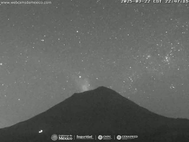 A dark, silhouetted volcano is visible under a clear, starry night sky.