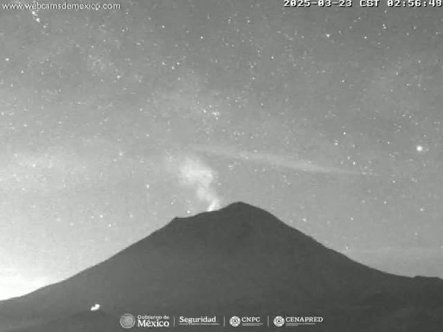 A dark, mountainous volcano erupts a small plume of smoke under a clear, starry night sky.
