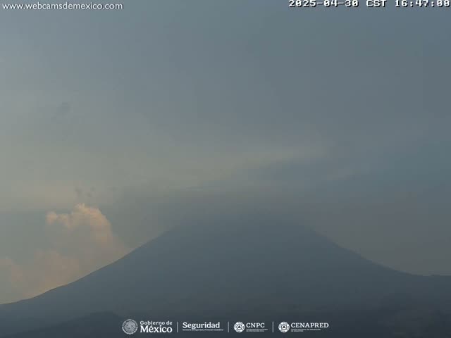 A hazy, overcast sky hangs over a large, dark mountain.