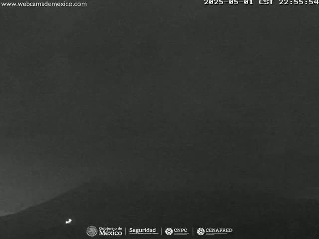 A dark, nighttime view of a mountain under a mostly clear sky.